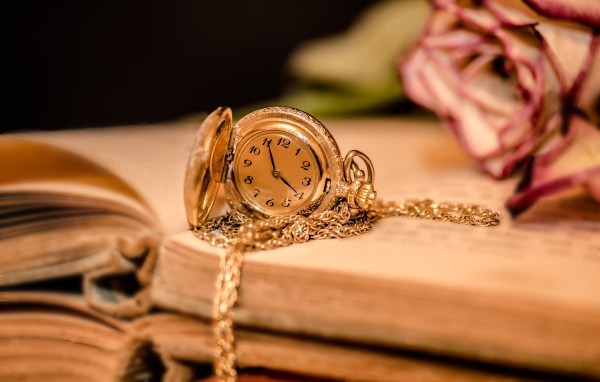 Золотые женские часы на цепочке лежат на книге