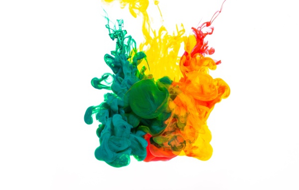 Зеленая и желтая краска растворяются в воде на белом фоне