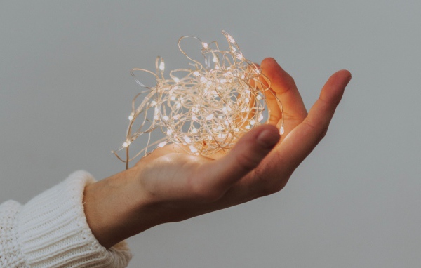 Включенная гирлянда в руке на сером фоне