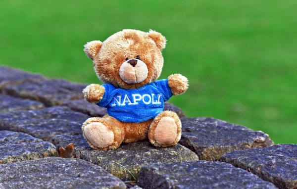 Маленький игрушечный медвежонок сидит на камнях 