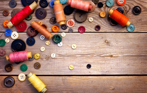 Разноцветные пуговицы и нитки лежат на столе