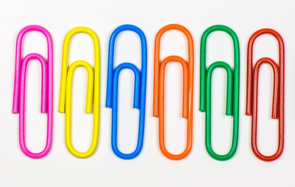 Разноцветные скрепки на белом фоне 