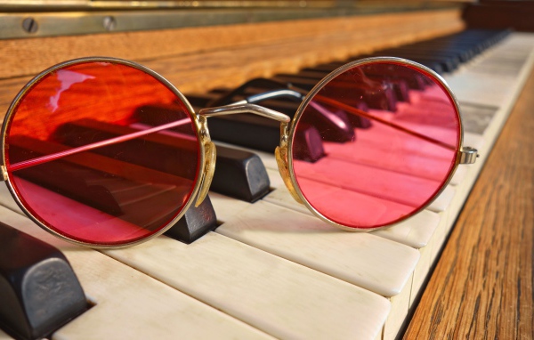 Розовые очки лежат на клавишах рояля