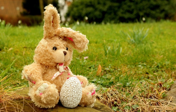 Игрушка заяц на камне в траве