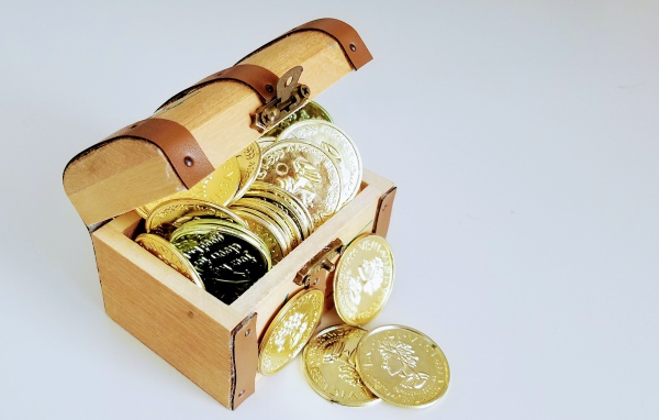 Золотые монеты в сундуке на сером фоне