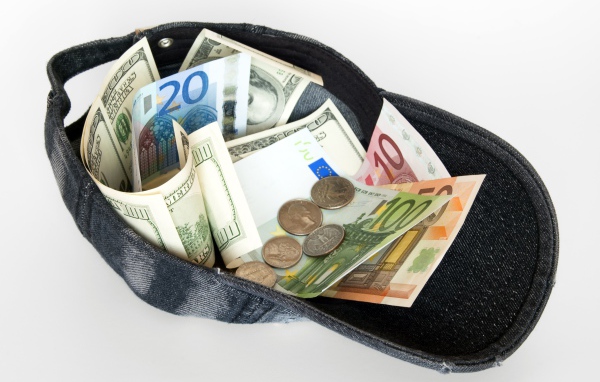 Бейсболка с купюрами и монетами на белом фоне