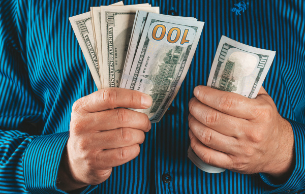 Мужчина считает сто долларовые купюры 