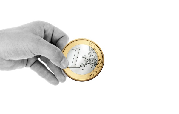 Монета в один евро в руке на белом фоне