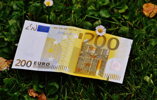 Купюра двести евро лежит на зеленой траве