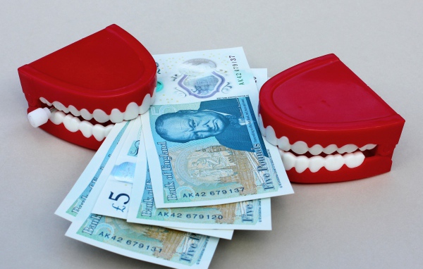 Два держателя денег в форме челюсти с купюрами на сером фоне