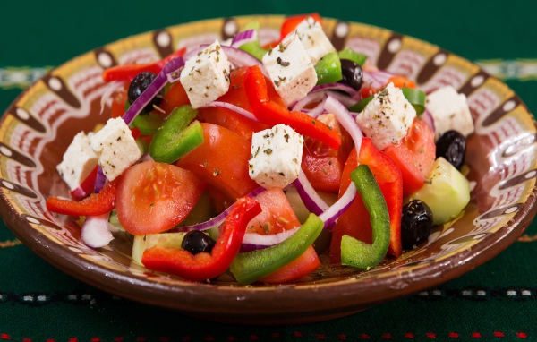 Аппетитный греческий салат в тарелке на столе