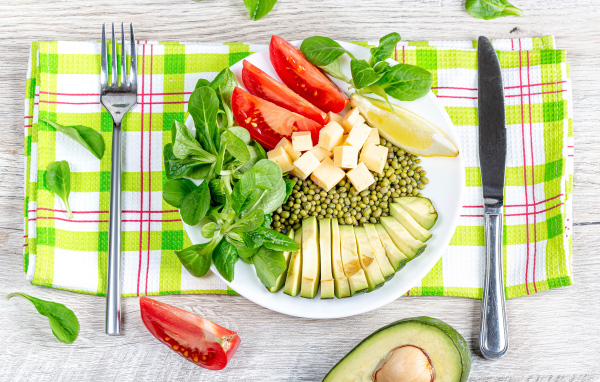 Аппетитные  свежие овощи с сыром и лимоном на тарелке 