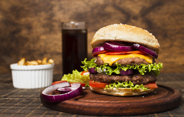 Большой гамбургер на столе с колой и картофелем фри 