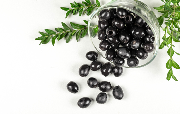 Черные маслины с розмарином на белом фоне