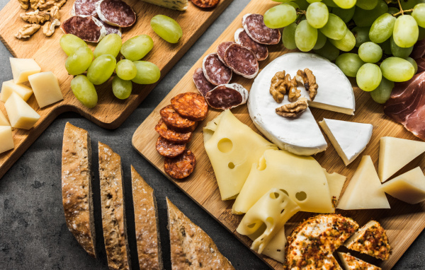 Сыр, колбаса, виноград и батон  на столе 