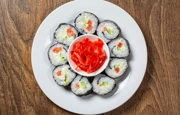 Вкусные суши на большой белой тарелке с имбирем