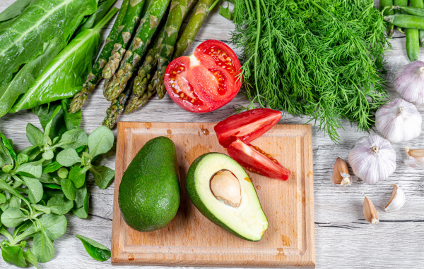 Свежая зелень на столе с авокадо, помидором и чесноком