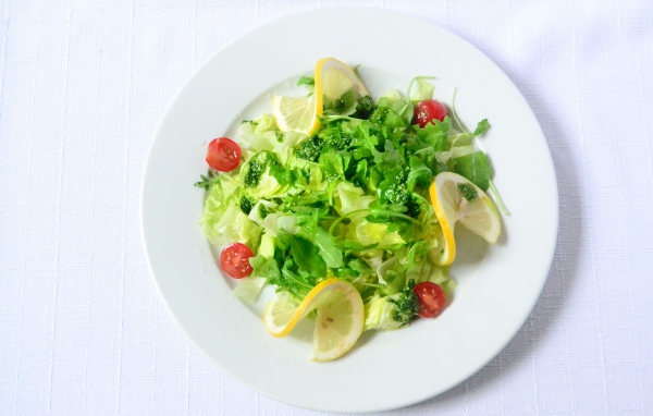 Салат из зелени с лимоном на белом фоне 