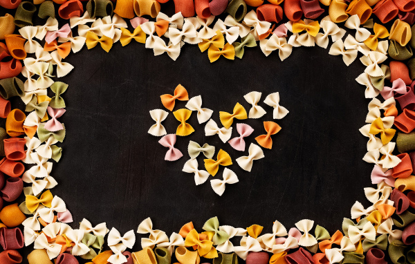 Сердце из разноцветных макарон на черном столе 