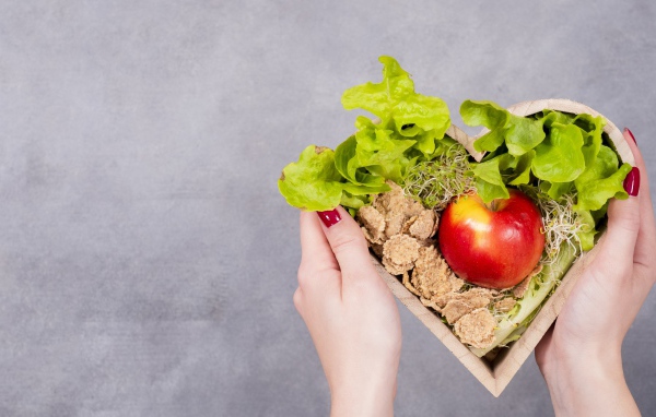 Коробка в форме сердца с яблоком и листьями салата 