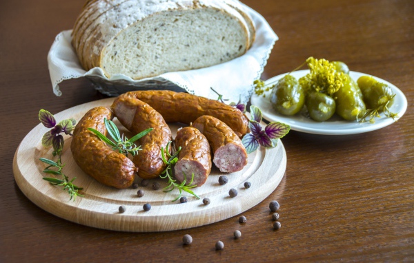Домашняя колбаса на столе с хлебом и маринованными огурцами