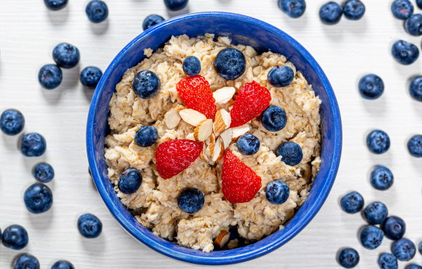 Овсяная каша в тарелке с ягодами черники и клубники 