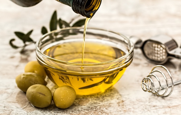 Оливковое масло в стеклянной тарелке на столе 