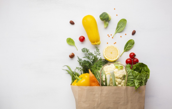 Пакет со свежими овощами и зеленью на сером фоне 