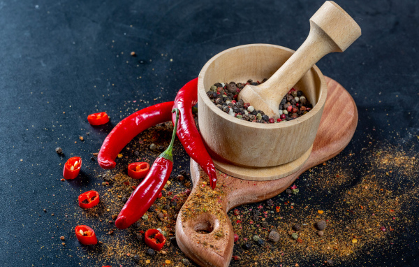 Перец горошком в ступке на столе с острым перцем