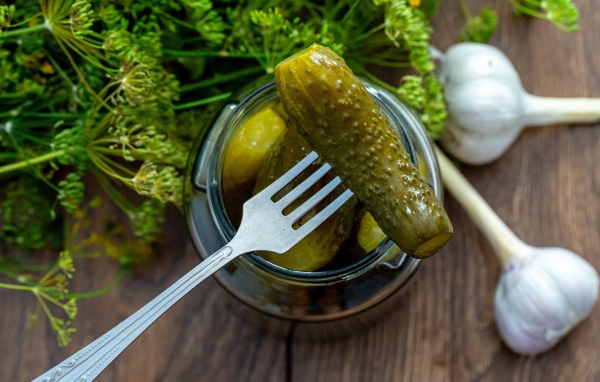 Маринованные огурцы в банке на столе с чесноком и укропом