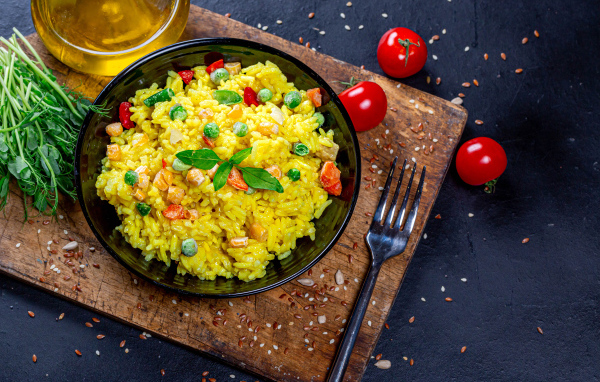 Рис с овощами на столе с маслом, зеленью и помидорами 