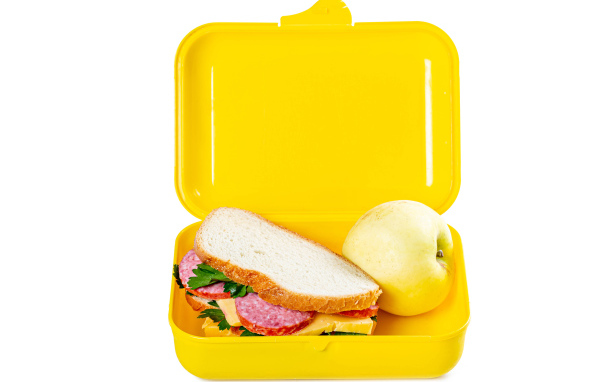 Бутерброд и яблоко в контейнере на белом фоне