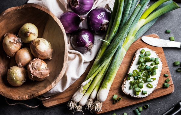 Бутерброд на столе с зеленым и репчатым луком