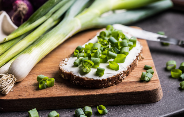 Бутерброд с маслом и зеленым луком на столе 
