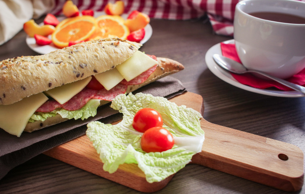 Бутерброды на столе с фруктами и чашкой чая