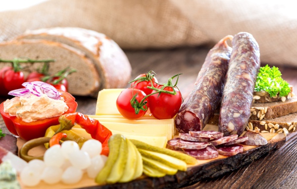 Колбаса на столе с огурцами, помидорами и перцем