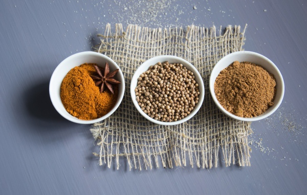 Специи в белых мисках на сером столе 