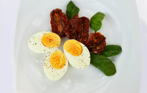 Вяленые помидоры на тарелке с базиликом и вареными яйцами
