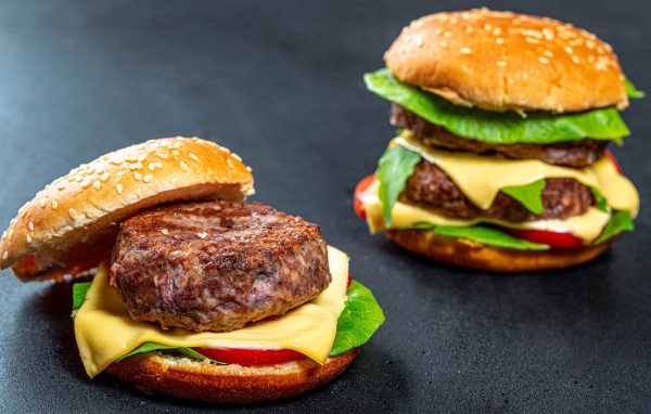 Два аппетитных гамбургера с сочной котлетой на сером фоне