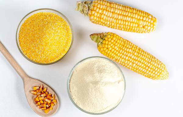 Два початка кукурузы на белом фоне с крупой и мукой 