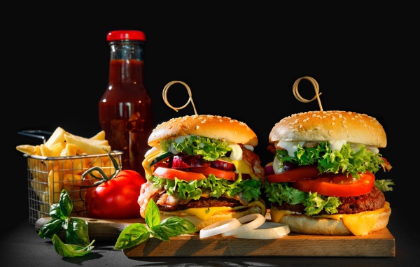 Два гамбургера на столе с картофелем фри, кетчупом и помидорами