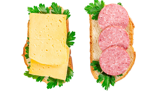 Два бутерброда с сыром,колбасой,петрушкой на белом фоне