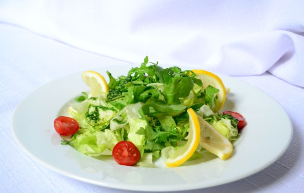 Белая тарелка со свежим зеленым салатом 