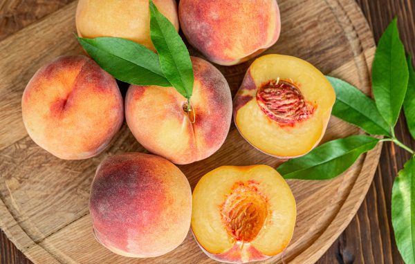 Аппетитные свежие персики на деревянной доске