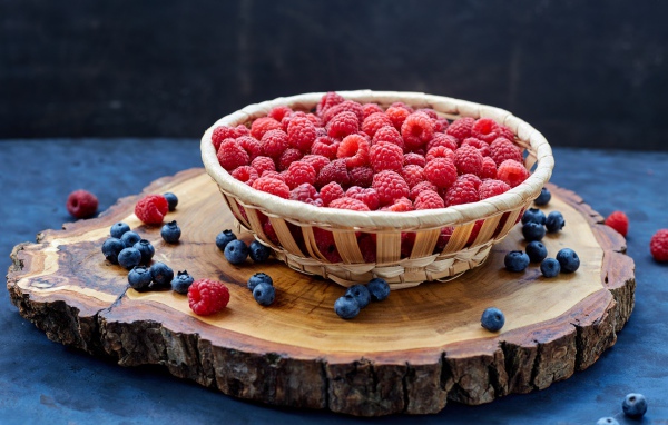 Корзинка с малиной на столе с ягодами черники