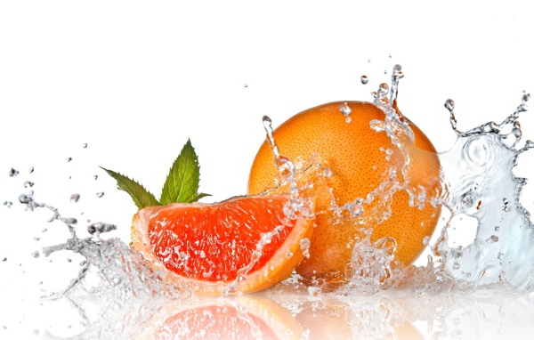 Большой спелый апельсин в брызгах воды на белом фоне