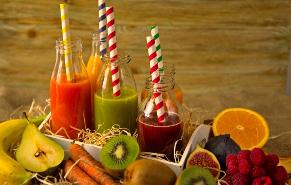 Бутылочки с соком на столе с фруктами 