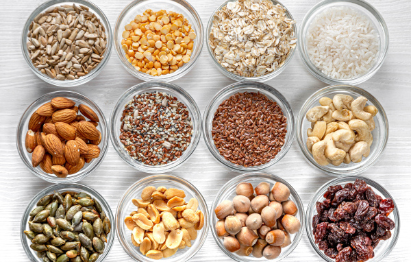 Разные виды орехов, круп и зерен в тарелках вид сверху 