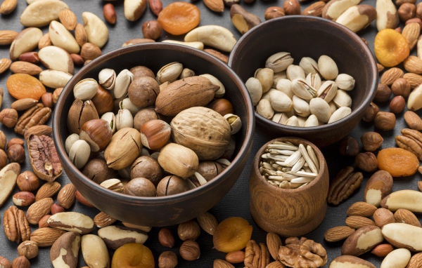 Разные виды орехов на столе в мисках 