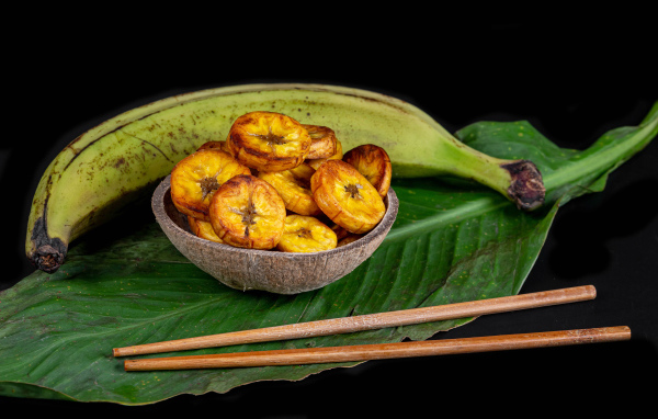 Сушеные бананы на столе с палочками и зеленым листом